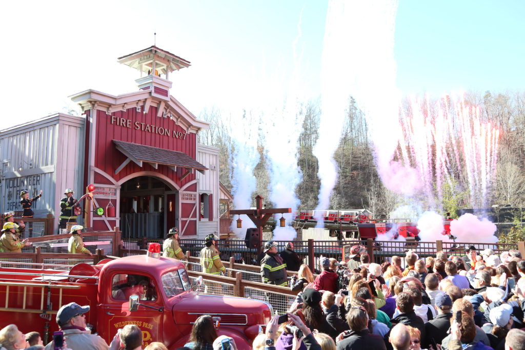 People line up outside fire station with red truck waiting to ride roller coaster