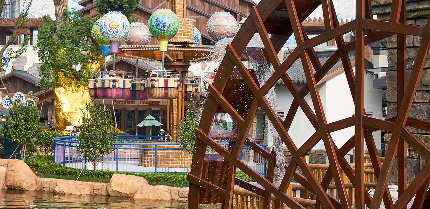 Wanda Nanchang Theme Park ride designed to look like hot air balloons with wooden water wheel in foreground