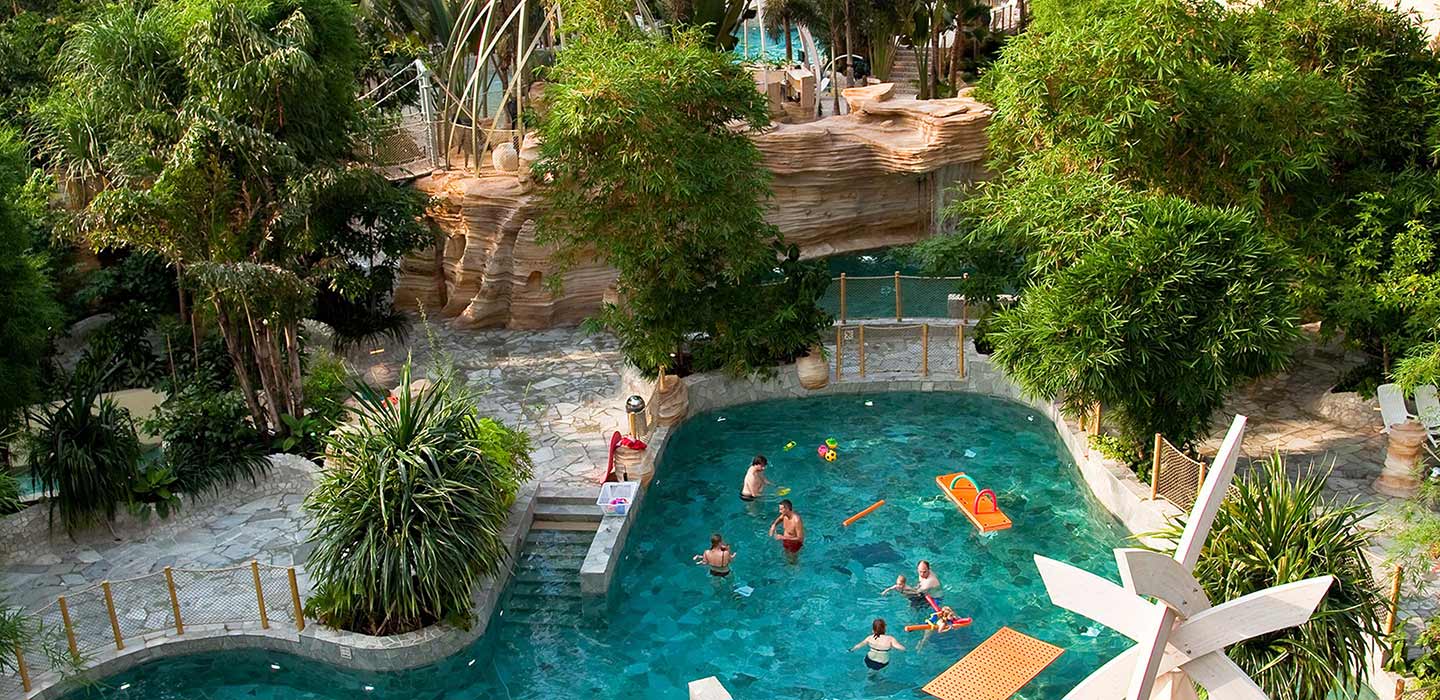 Pool surrounded by greenery and rock deck at the Center Parcs Domaine des Trois Forets
